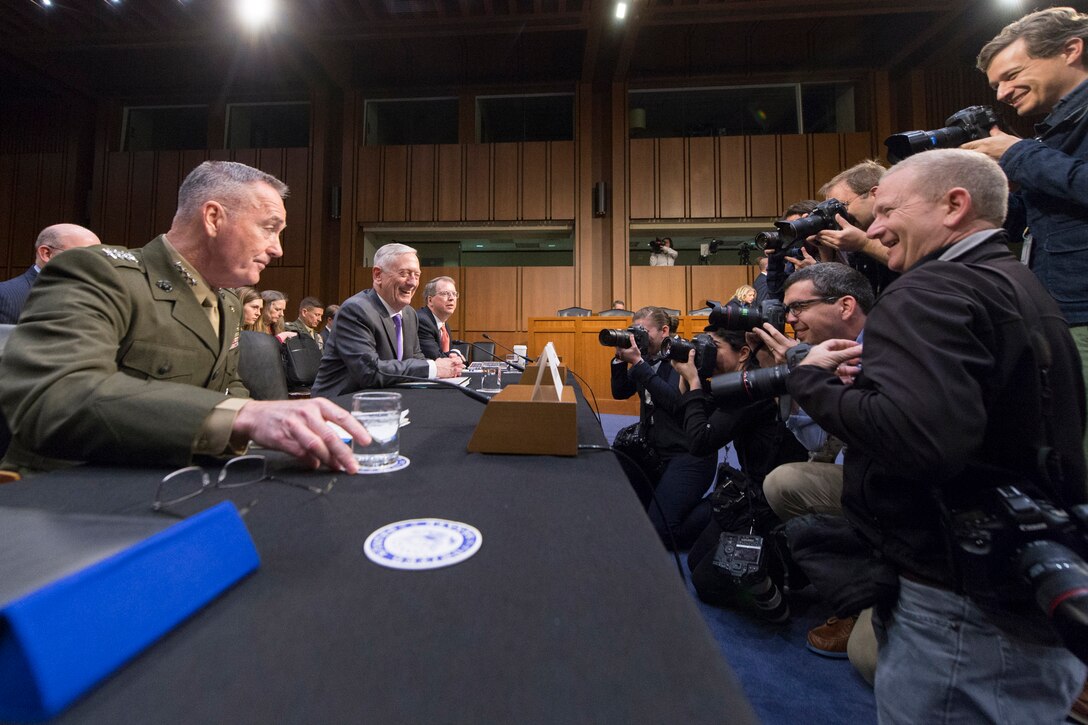 Photographers take pictures of Marine Corps Gen. Joe Dunford and Defense Secretary James N. Mattis as they sit at a table.