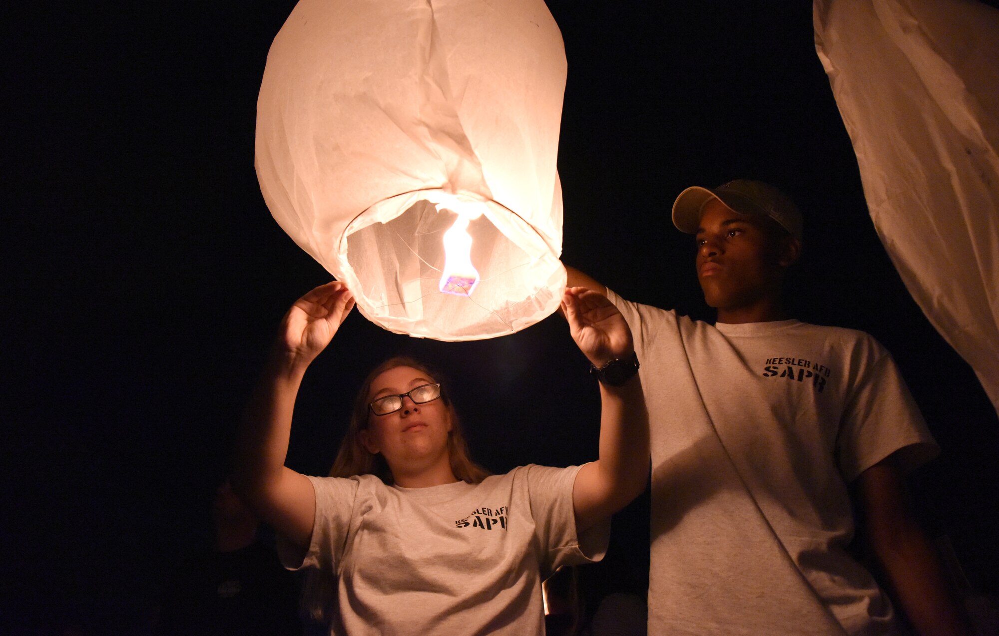 U.S. Air Force Airman 1st Class Tory Battles, and Airman Stephen Chapa, 336th Training Squadron students, prepare to let go of a sky lantern during a sky lantern vigil on Biloxi Beach, Mississippi, Sept. 27, 2018. In recognition of suicide prevention and awareness month, the 81st Medical Operations Squadron mental health team hosted the themed event, Lights For Life, to honor the memories of victims of suicide. (U.S. Air Force photo by Kemberly Groue)