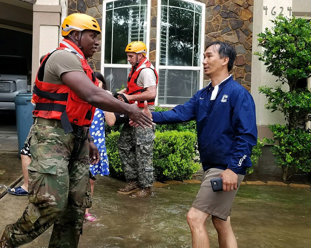 A soldier shakes hands with a resident.