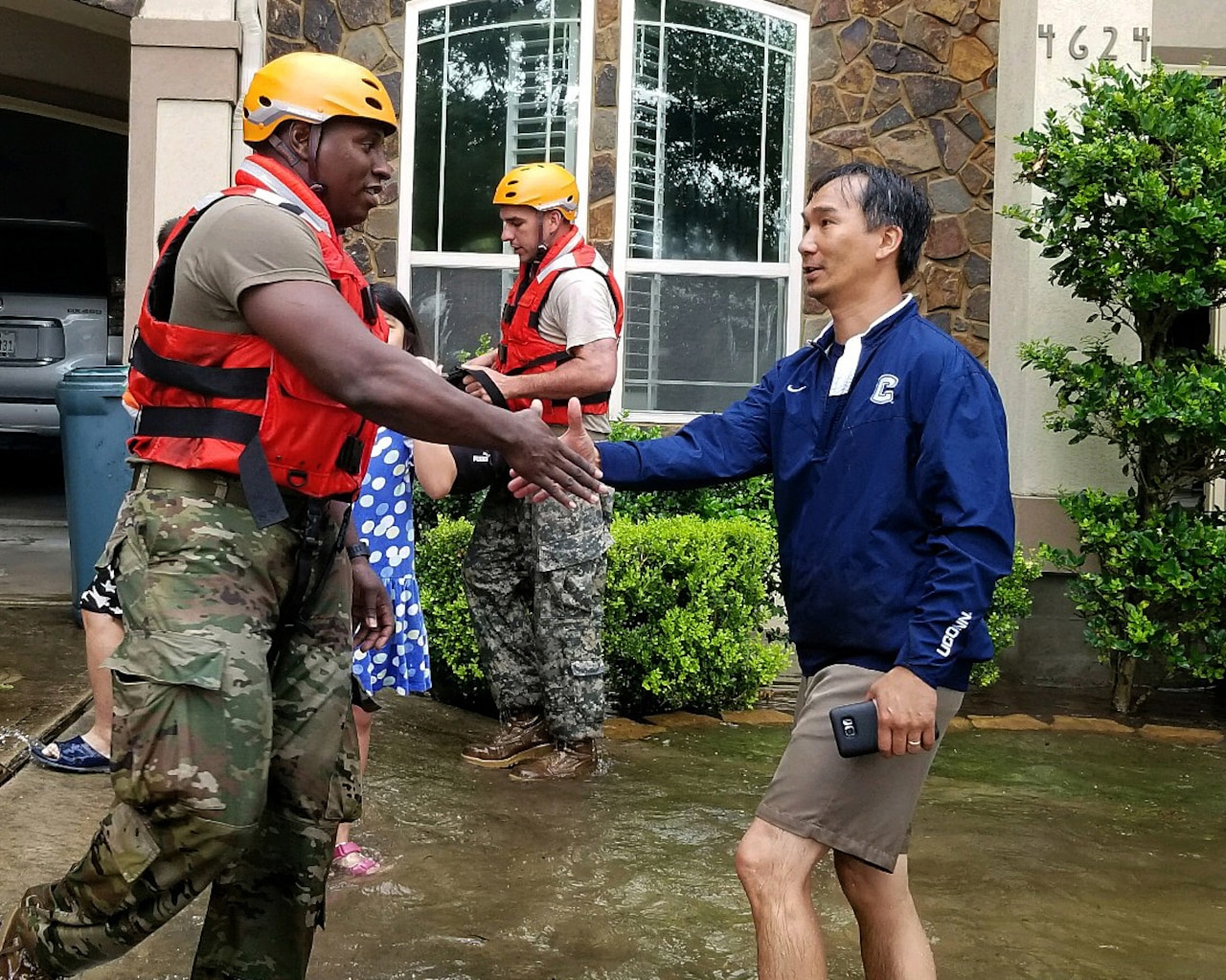 A soldier shakes hands with a resident.