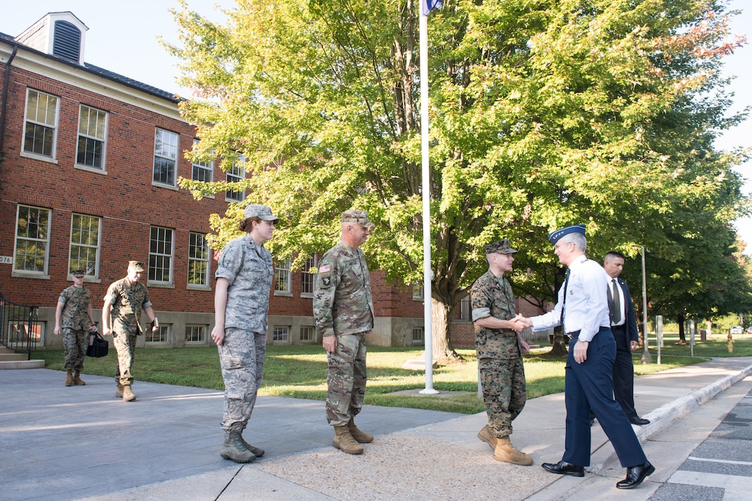 Air Force Gen. Paul J. Selva, vice chairman of the Joint Chiefs of Staff, shakes hands with a Marine outside a red brick building.