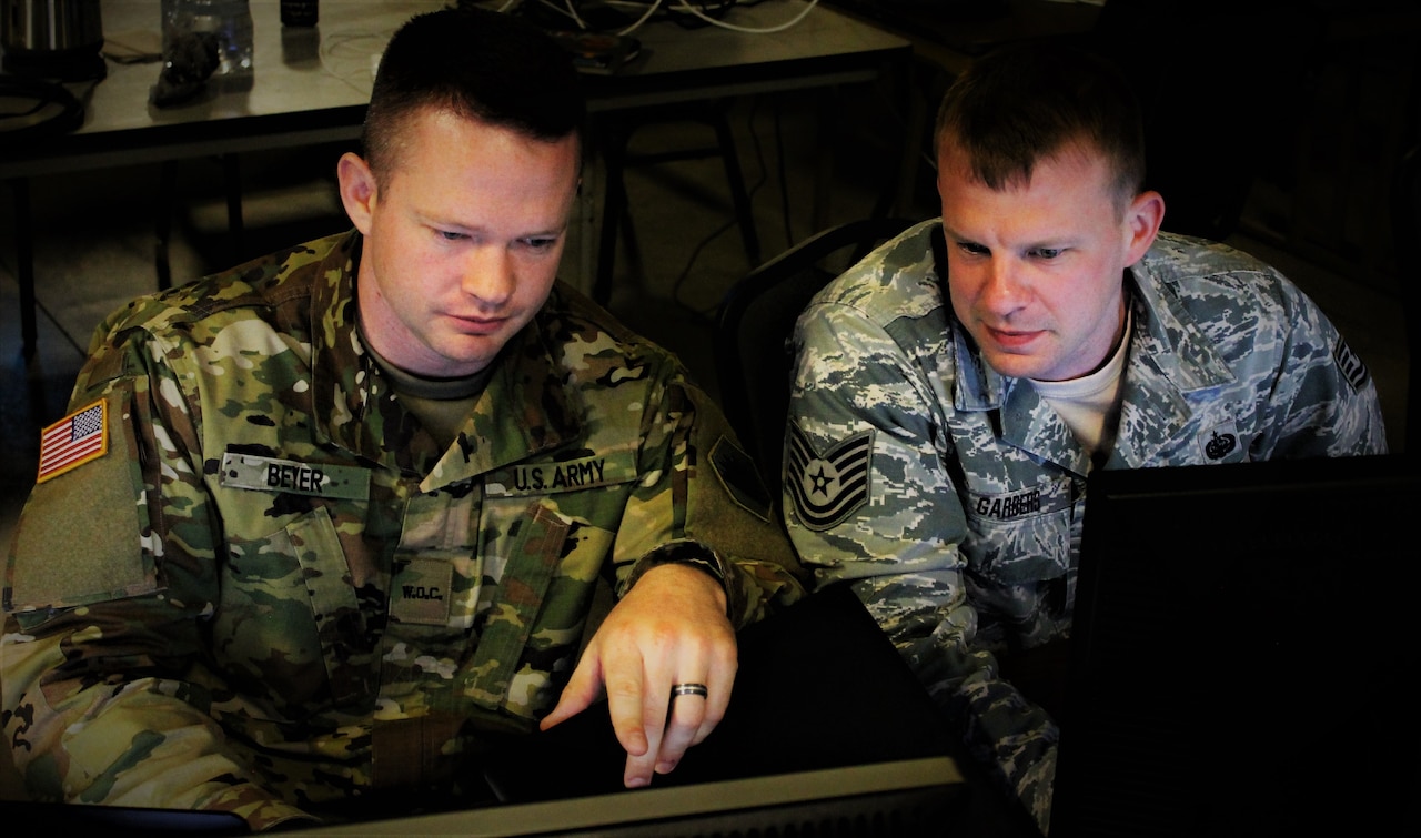 Two men sit at a computer.