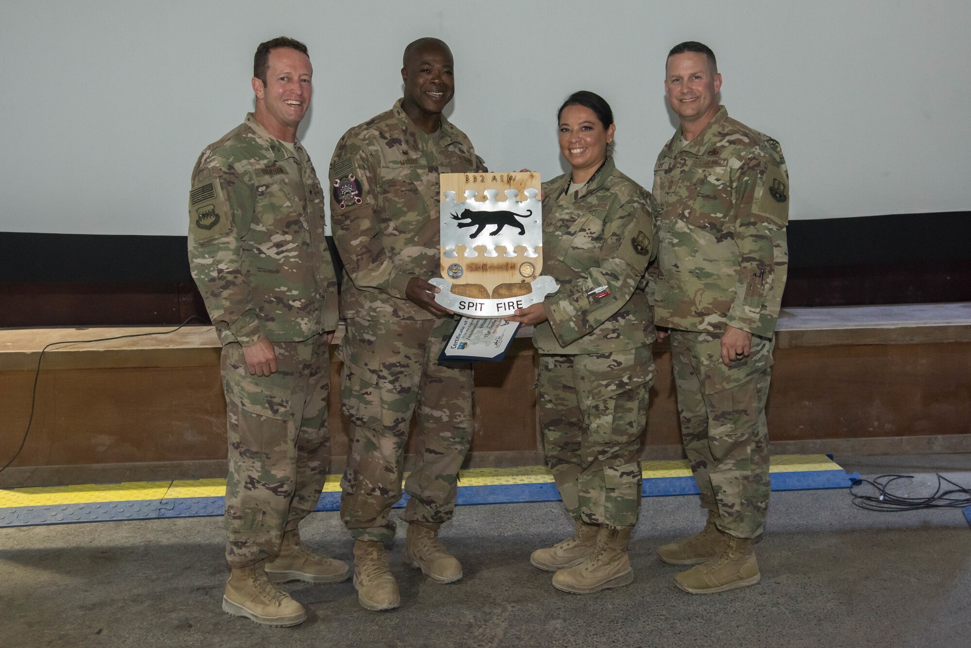Brig. Gen. David Iverson, 332nd Air Expeditionary Wing commander, and Chief Master Sgt. Jason Tiek, 332nd AEW command chief, present the Red Tails Commander’s Innovation Challenge traveling trophy to Tech. Sgt. Oralia Howard, 332nd Expeditionary Maintenance Group quality assurance chief inspector, and Col. Henry Myers Jr., 332nd EMXG commander, Sept. 28, 2018 at an undisclosed location in Southwest Asia.