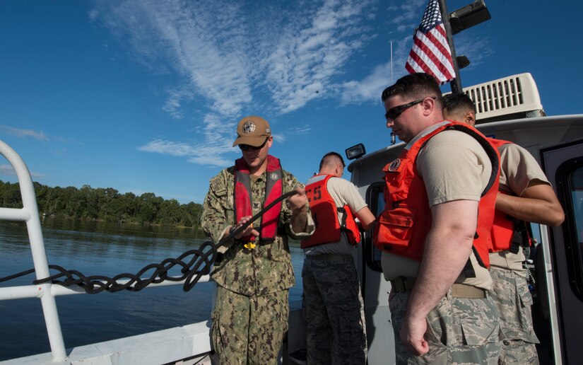 U.S. Navy Master-at-Arms 2nd class Bryan Mead, left, 628th Security Forces Squadron Shore Installation Management Basic Boat Coxswain Course instructor, teaches U.S. Air Force Airmen how to tie a rope during a SIMBBC practical exercise Sept. 26, 2018, at Joint Base Charleston’s Naval Weapons Station, S.C. The SIMBBCC curriculum arms security forces members with skills needed to conduct harbor patrol missions and covers techniques including man overboard drills, pier approaches, towing and anchoring.