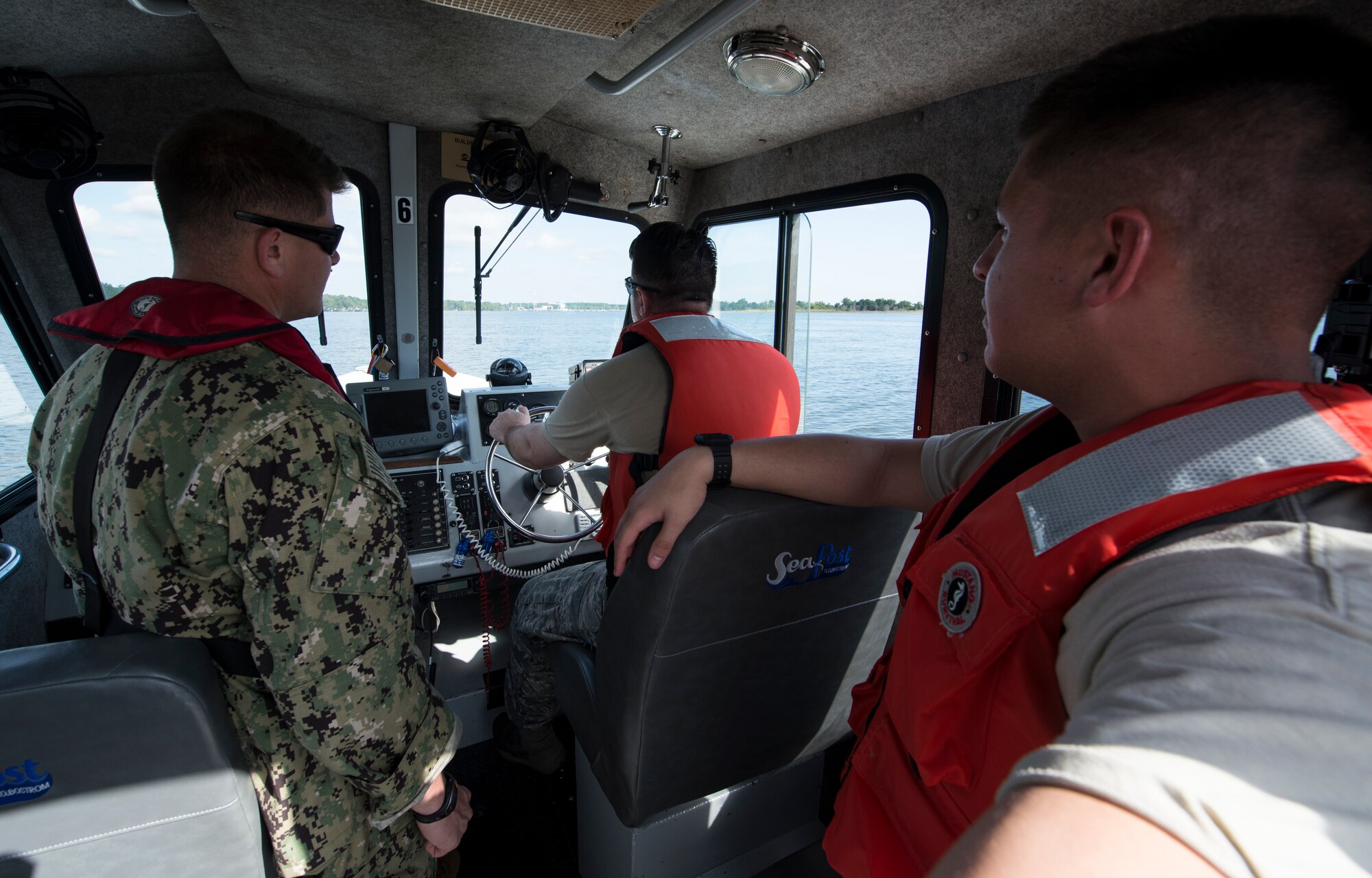 U.S. Navy Master-at-Arms 2nd class Bryan Mead, left, 628th Security Forces Squadron Squadron Shore Installation Management Basic Boat Coxswain Course instructor, teaches Airmen how to navigate a boat during a SIMBBC practical exercise Sept. 26, 2018, at Joint Base Charleston’s Naval Weapons Station, S.C. The SIMBBCC curriculum arms security forces members with skills needed to conduct harbor patrol missions and covers techniques including man overboard drills, pier approaches, towing and anchoring.