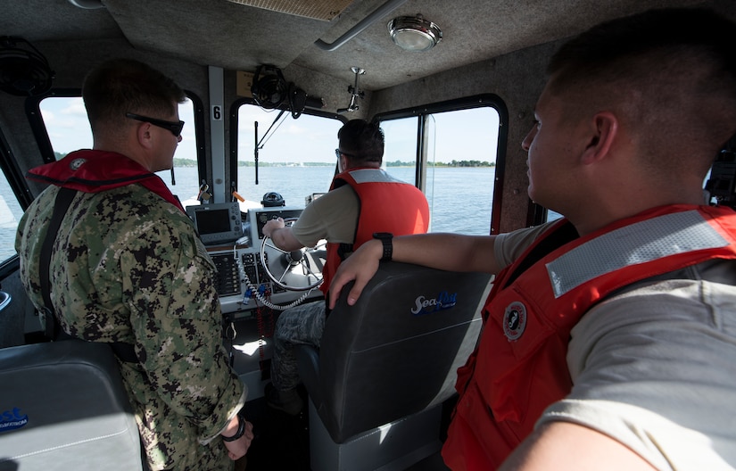 U.S. Navy Master-at-Arms 2nd class Bryan Mead, left, 628th Security Forces Squadron Squadron Shore Installation Management Basic Boat Coxswain Course instructor, teaches Airmen how to navigate a boat during a SIMBBC practical exercise Sept. 26, 2018, at Joint Base Charleston’s Naval Weapons Station, S.C. The SIMBBCC curriculum arms security forces members with skills needed to conduct harbor patrol missions and covers techniques including man overboard drills, pier approaches, towing and anchoring.