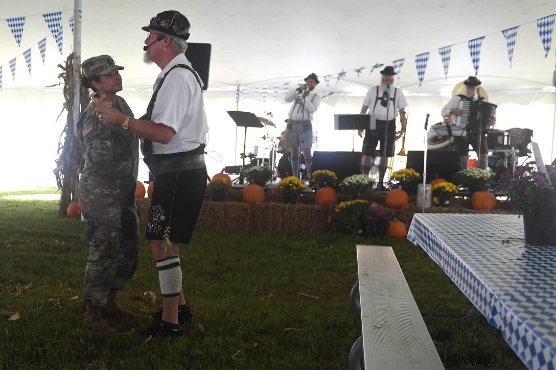 U.S. Army First Sergeant Taelimu Herrera, Headquarters and Headquarters Company, 7th Transportation Brigade (Expeditionary) first sergeant, dances with a member of the Happy Dutchmen during Oktoberfest at Joint Base Langley-Eustis, Virginia, Sept. 28, 2018. The Oktoberfest festival traditionally marks the beginning of the fall season. (U.S. Air Force photo by Senior Airman Derek Seifert)