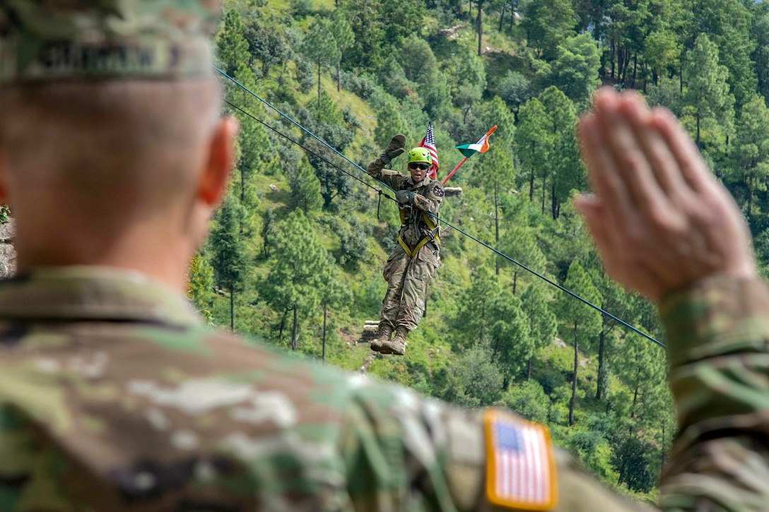 A soldier takes the oath of enlistment hanging off a zip line.