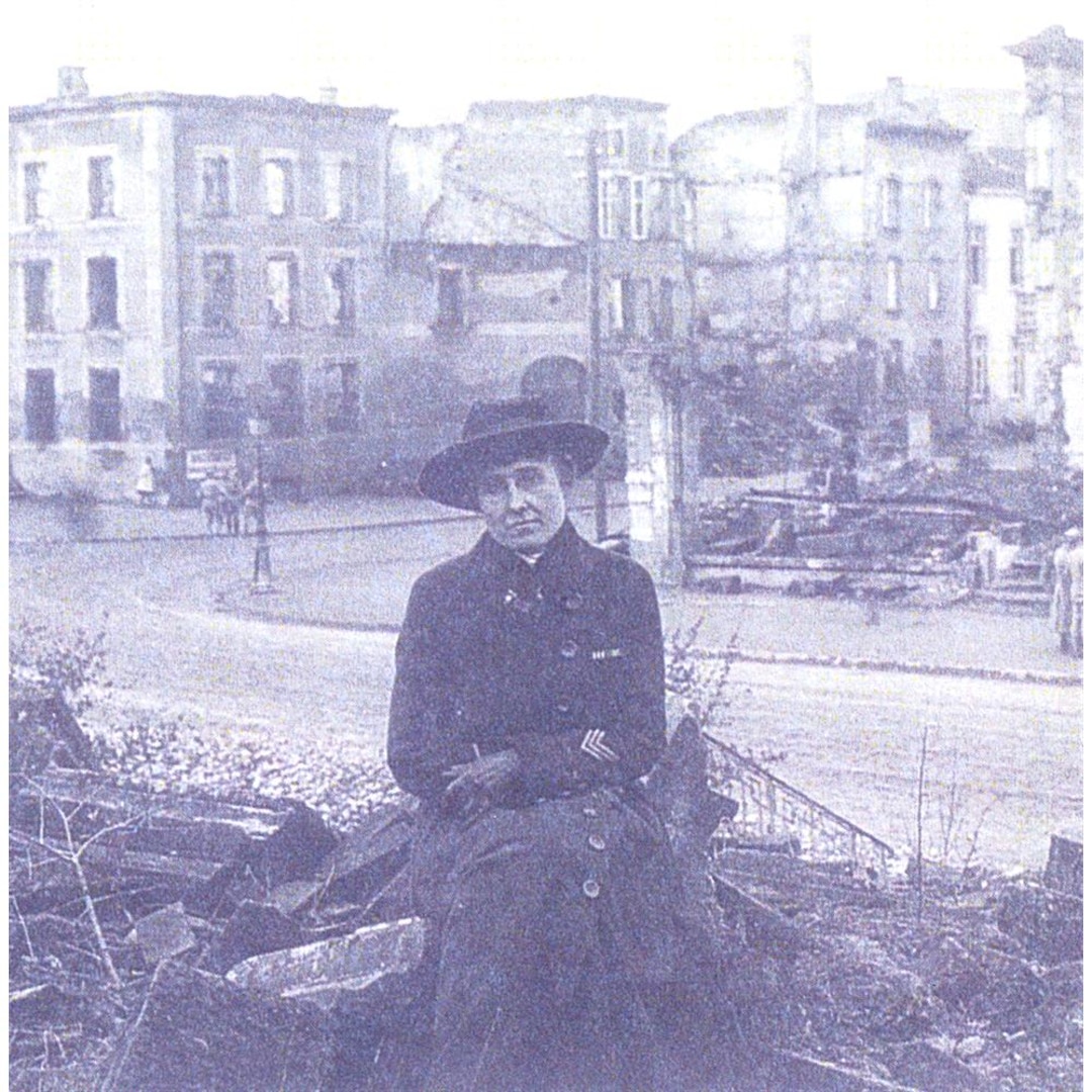 A historic photo of a woman sitting in rubble.