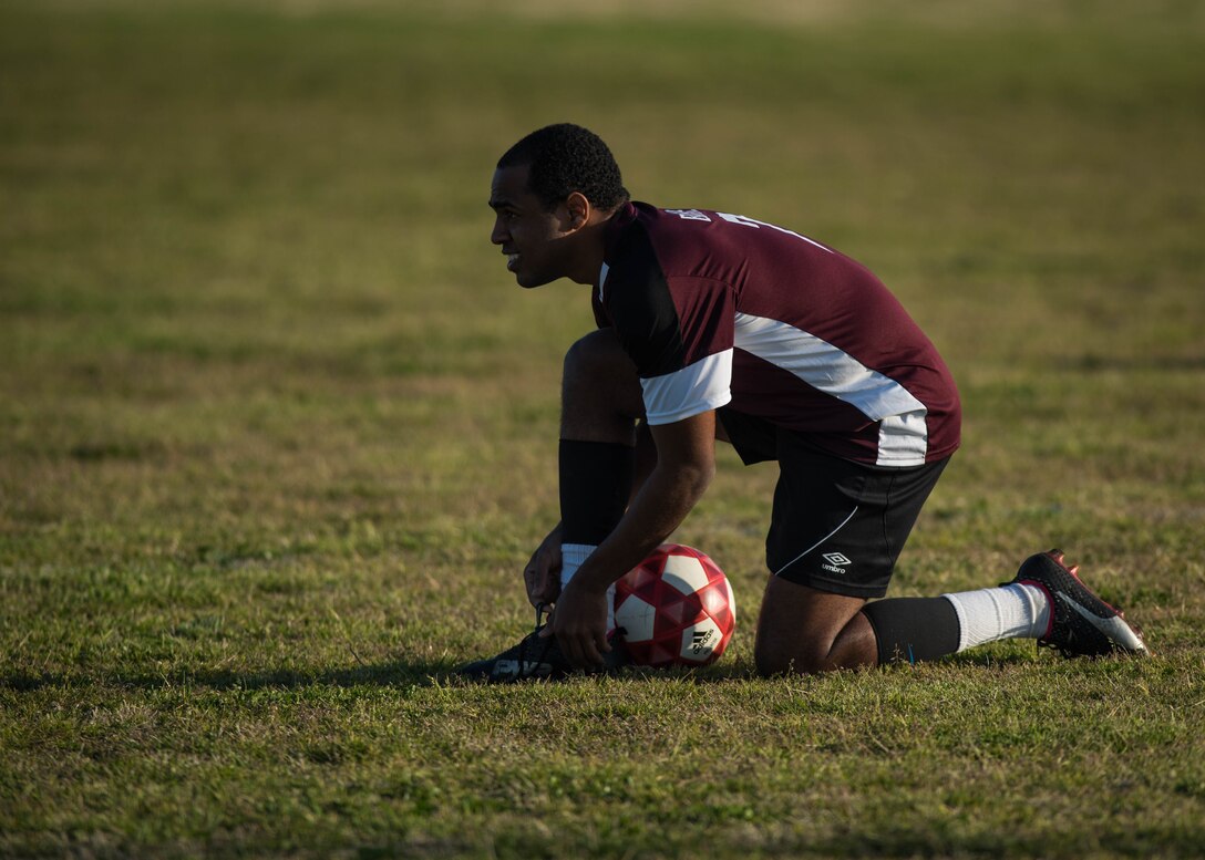 U.S. Air Force Airman 1st Class Jairzinho Burke, 633rd Air Base Wing Judge Advocate paralegal, tightens his laces during an intramural soccer game at Joint Base Langley-Eustis, Virginia, April 12, 2018. Burke played soccer on semi-pro team “Villages Football Club” in Orlando, Florida, during the summer of 2016. (U.S. Air Force photo by Airman 1st Class Anthony Nin Leclerec)