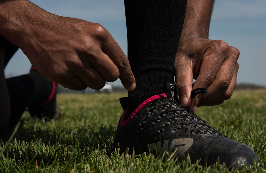 U.S. Air Force Airman 1st Class Jairzinho Burke, 633rd Air Base Wing Judge Advocate paralegal, ties his shoelaces at the Joint Base Langley-Eustis, Virginia, soccer field April 13, 2018.