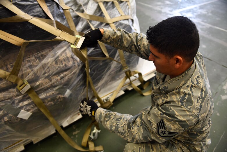U.S. Air Force Staff Sgt. Joseph Needham, 92nd Logistics Readiness Squadron NCO in charge of passenger services, straps down cargo in preparation for loading at Fairchild Air Force Base, Washington, September 2018. Mobility Airmen fuel the fight, provide airlift needed for supplies and personnel, and enable versatile and timely effects through contingency response ensuring mission success. (U.S. Air Force photo/Airman 1st Class Lawrence Sena)