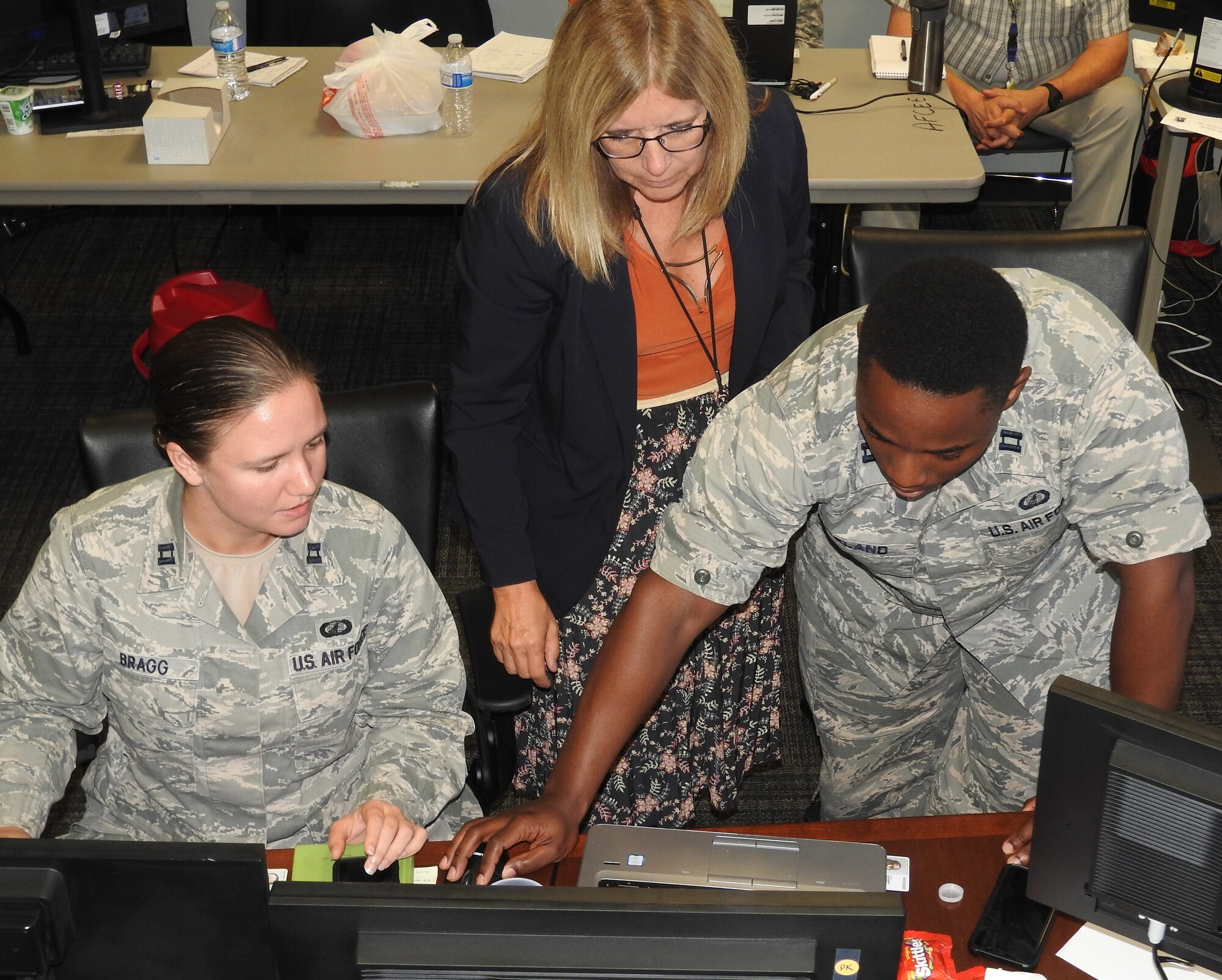 Jo Moyer, AFIMSC Defense Enterprise Accounting and Management System specialist, assists Capts. Amy Bragg and Julian Ireland, AFIMSC Detachment 8 budget analysts, with the set up of a new reconciling tool that will help them validate DEAMS accounting and financial data. (U.S. Air Force Photo by Ed Shannon)