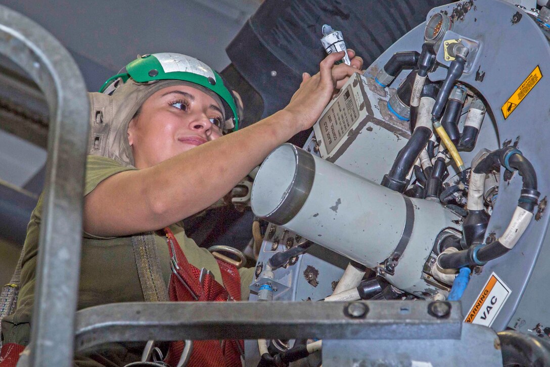 A woman works on an aircraft engine.