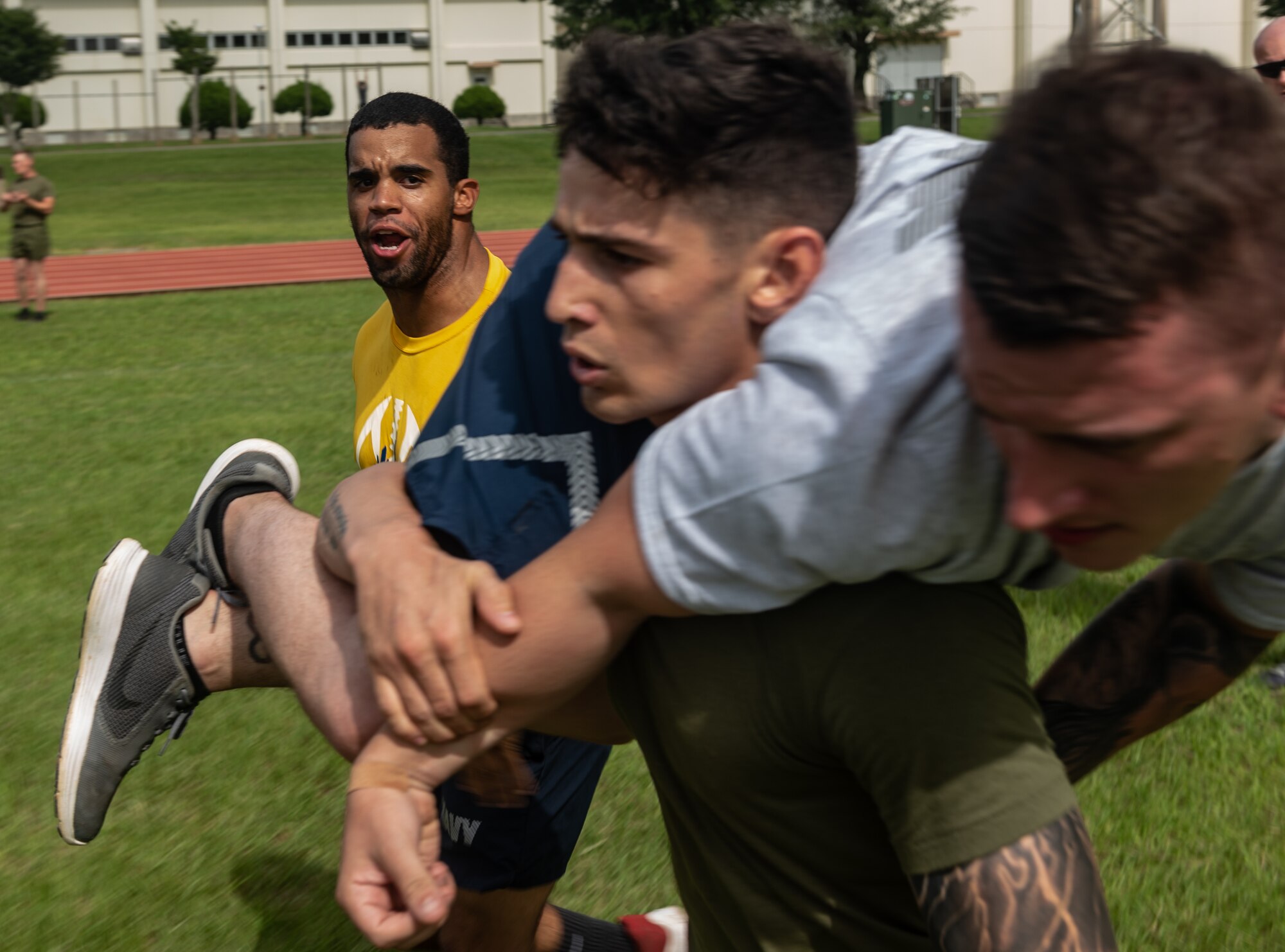 U.S. Navy Petty Officer 2nd Class Jesse Pedrero motivates U.S. Marine Corps Sgt. Cory Gargus while he carries U.S. Air Force Staff Sgt. Monty Baze, Okinawa Joint Experience Green Team students, during the Okinawa Joint Fitness Challenge Sept. 26, 2018, at Kadena Air Base, Japan. Service members from the Army, Navy, Air Force and Marine Corps were equally broken up into four classes to provide a joint learning environment. (U.S. Air Force photo by Staff Sgt. Micaiah Anthony)