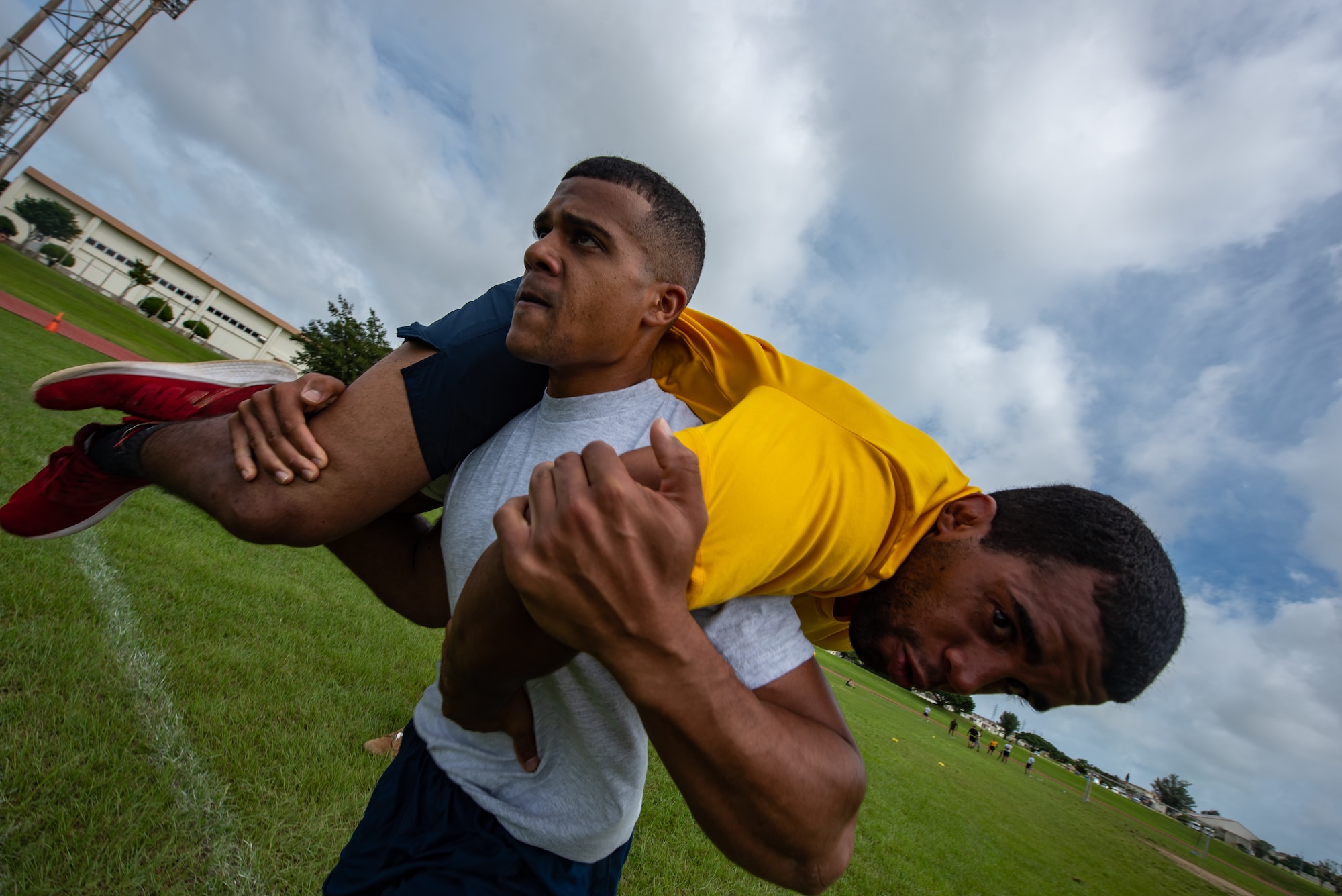 U.S. Air Force Staff Sgt. Thomas Nollie carries U.S. Navy Petty Officer 2nd Class Jesse Pedrero, both Okinawa Joint Experience Green Team students, during the Okinawa Joint Fitness Challenge Sept. 26, 2018, at Kadena Air Base, Japan. The OJFC was designed to mimic obstacles and challenges faced in the battlefield such as sprinting, running ammunition cans, transporting wounded personnel to safety and tossing simulated grenades. Each team competed for the best time, however the final challenge brought all four teams together. (U.S. Air Force photo by Staff Sgt. Micaiah Anthony)