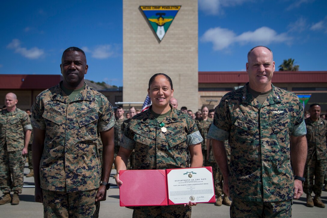 Master Sergeant Duffel of Marine Corps Air Station Camp Pendleton Ordinance Department stands next to Sergeant Major Robinson and Colonel Clark with her award for excellence as the Ordinance Chief.