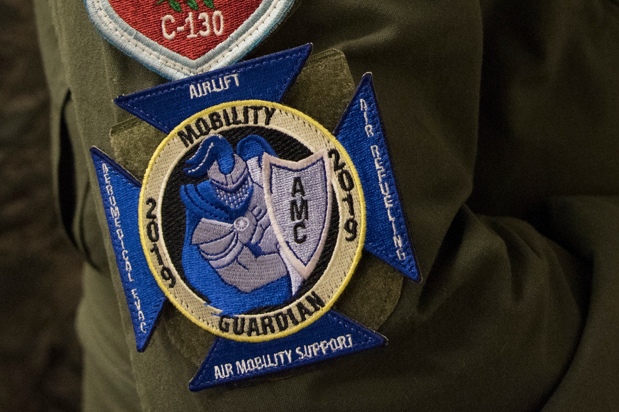 An international attendee wears the ceremonial patch of Mobility Guardian 2019 at the International Planning Conference held at Fairchild Air Force Base, Washington, Sept. 19, 2018. Partner forces don’t always use the same equipment or similar operating procedures, so familiarization via training with other forces helps everyone know other military capabilities and compatibilities. (U.S. Air Force photo/Senior Airman Ryan Lackey)