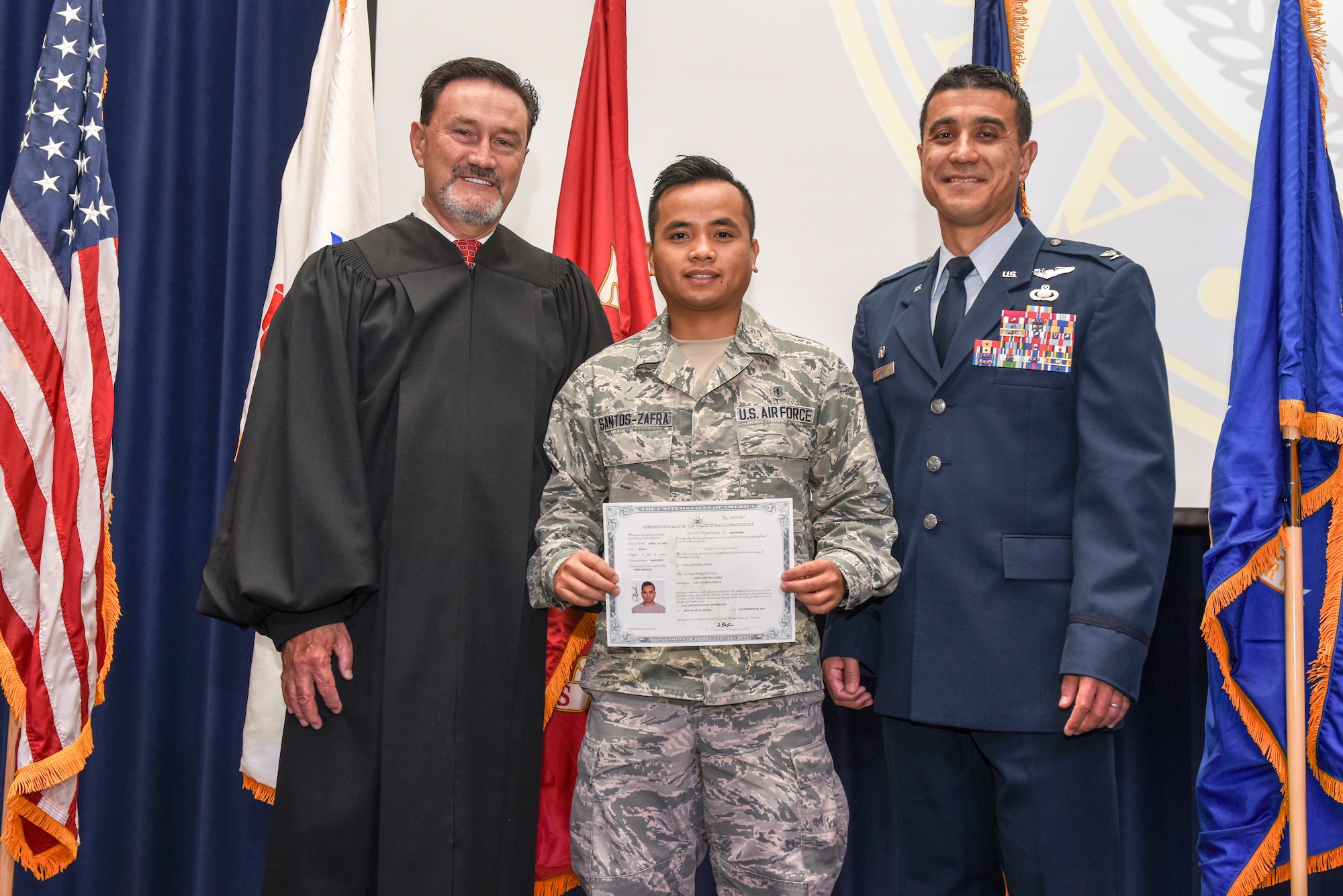 U.S. Magistrate Judge E. Scott Frost, U.S. Air Force Senior Airman John Santos Zafra, 17th Medical Operations Squadron public health technician and  Col. Ricky Mills, 17th Training Wing commander, pose after the naturalization ceremony held at the CJ Davidson Center on Angelo State University, San Angelo, Texas, Sept. 25, 2018. Zapfra was born in the Phillipines and moved to the U.S. when was 13 to live in Burleson, Texas. (U.S. Air Force photo by Aryn Lockhart/Released)