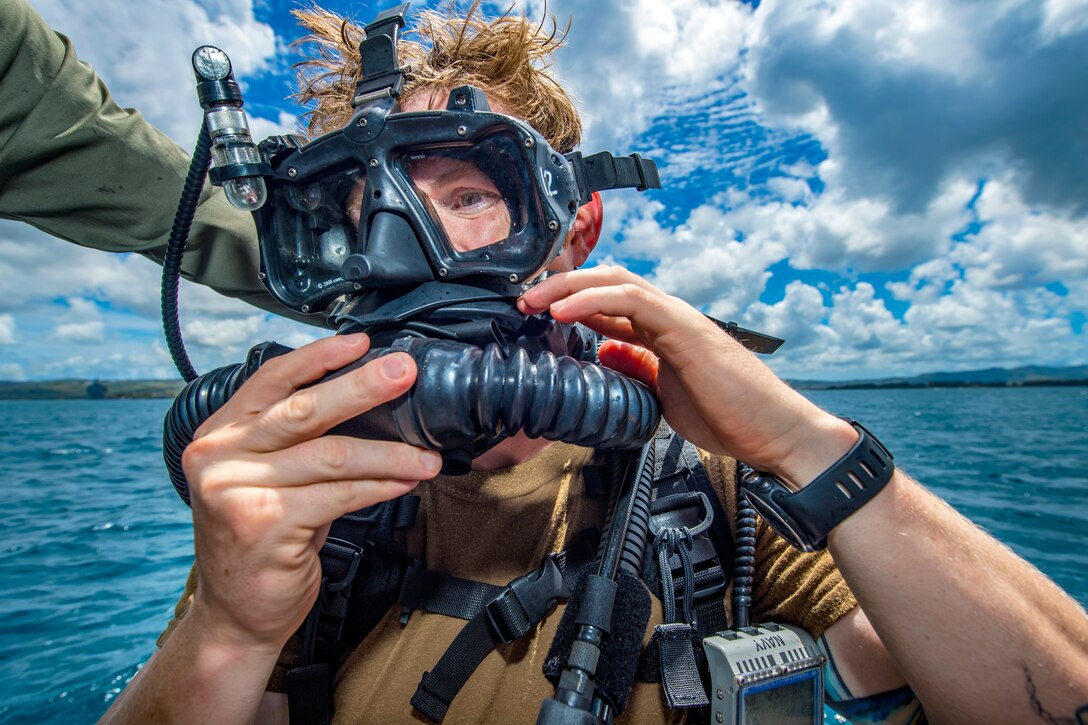 A sailor puts on a breathing apparatus with a mask.