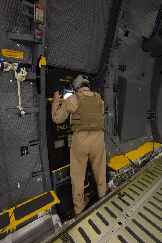 Tech. Sgt. David Bass, 22nd Airlift Squadron C-5M Super Galaxy loadmaster, demonstrates how he would look out the window of one of the aircraft’s troop doors to identify potential threats if the aircraft was flying through a hostile environment, at Travis Air Force Base, Calif., Sept. 12. Research is under way to implement a safer way for Air Force crew members to identify potential threats during flight. (U.S. Air Force photo by Tech. Sgt. James Hodgman)