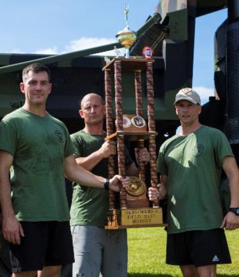 The Headquarter & Headquarters Squadron command staff – executive officer Maj. Richard Moritz, left, Sgt. Maj. Christopher Davis, center, and commanding officer Lt. Col. Christopher Benfield – face the final daunting task of carrying the enormous trophy off the field after participating in the annual Field Meet, beating Marine Wing Headquarters Squadron 2 at Marine Corps Air Station Cherry Point, N.C., Aug. 31, 2018. Marines from H&HS and MWHS-2 went head to head in the competition to determine which headquarters squadron is the best on MCAS Cherry Point. (Marine Corps photo by Lance Cpl. Andrew King)