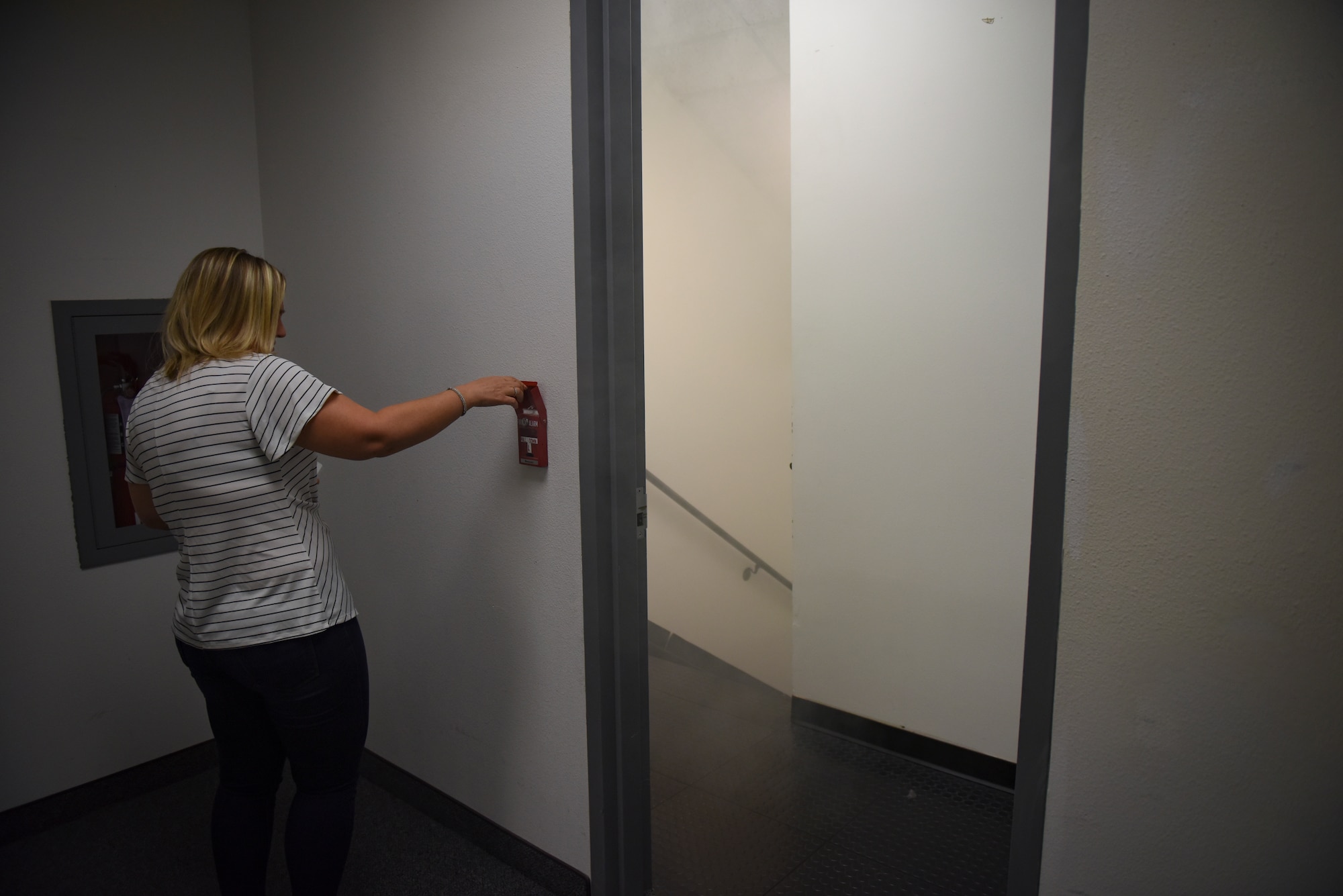 A member of the Nevada Test and Training Range pulls the fire alarm during a fire drill at Nellis Air Force Base, Nevada, Oct. 4, 2018. There are many fire hazards that are present in administrative work facilities where the employees must be trained on the proper safety procedures. (U.S. Air Force photo by Airman 1st Class Andrew D. Sarver)