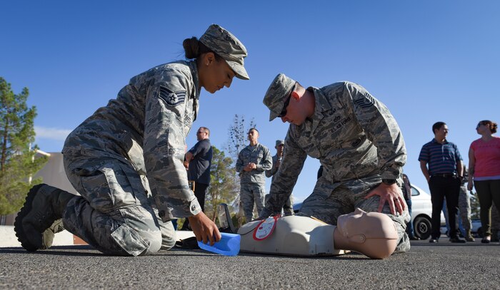 Staff. Sgt. Jordan Holmes, Nevada Test and Training Range occupational safety team member, and Tech. Sgt. Jeremy Cunningham, NTTR target shop flight chief, perform CPR on a dummy during a fire drill at Nellis Air Force Base, Nevada, Oct. 4, 2018. Air Force units are required to have trained personnel who can perform CPR and use an Automated External Defibrillator. (U.S. Air Force photo by Airman 1st Class Andrew D. Sarver)