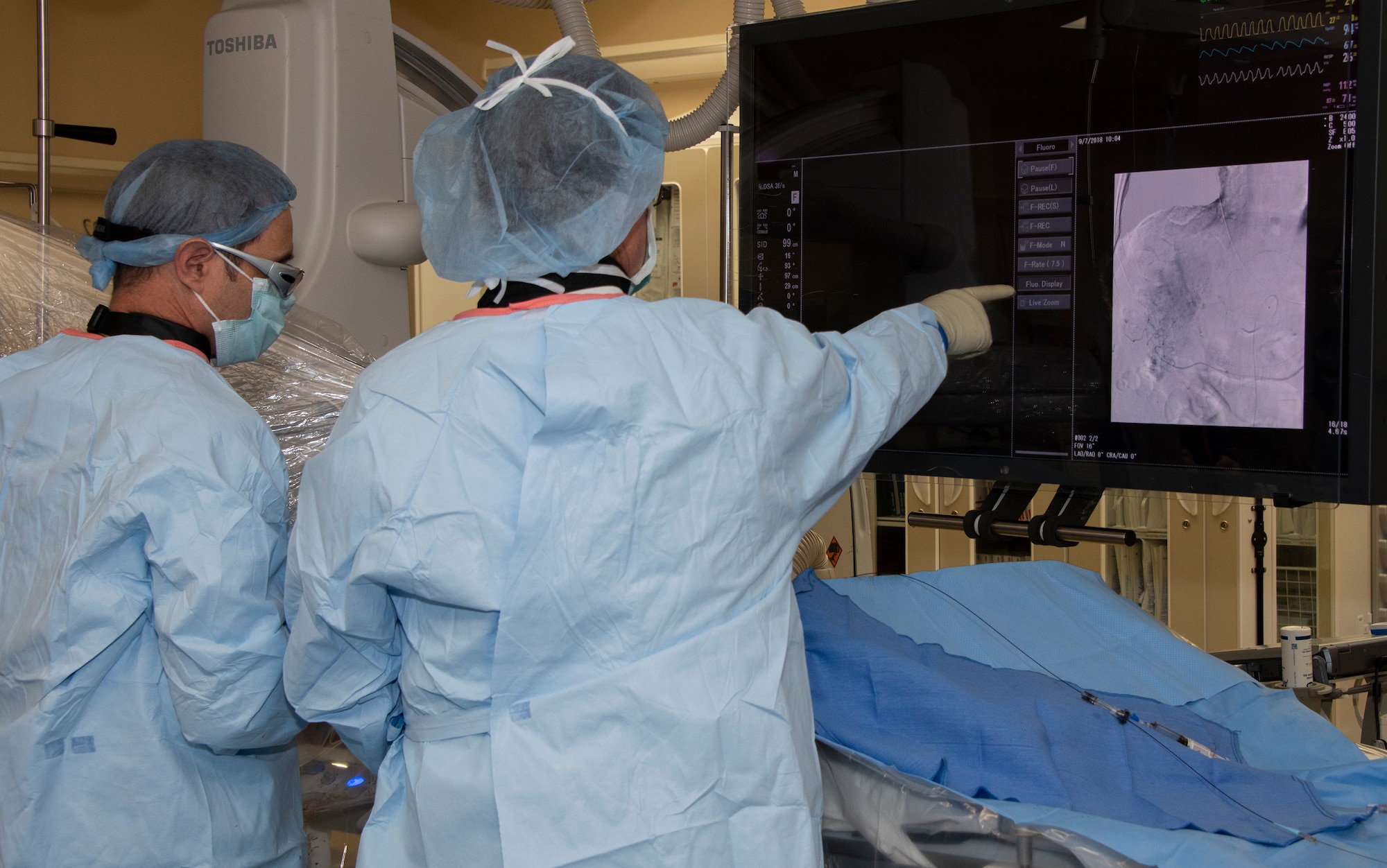 U.S. Air Force Lt. Col. (Dr.) David Gover and Maj. (Dr.) Jason Hoskins, 60th Medical Group interventional radiologists at David Grant U.S. Air Force Medical Center conduct an Yttrium-90 radioembolization procedure on a patient with liver cancer, Sept. 7, 2018, Travis Air Force Base, Calif. The Y-90 radioembolization is an advanced and minimally invasive method utilized for this disease by delivering millions of tiny radioactive beads inside the blood vessels that feed a tumor. The high dose of targeted radiation prospectively kills the tumor while sparing normal tissue. This was the first time the treatment was performed at DGMC. (Photo altered for security reasons) (U.S. Air Force photo illustration by Heide Couch)