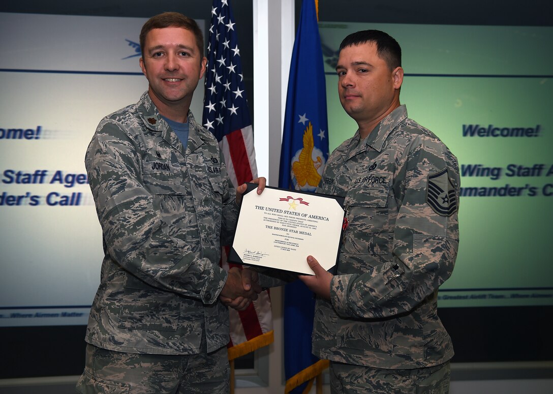 Maj. Steven P. Jordan, 62nd Comptroller Squadron commmander, presents a Bronze Star Medal award to Master Sgt. Kevin R. Peterson, 62nd Airlift Wing command post superintendent, inside the 4th Airlift Squadron on Joint Base Lewis-McChord, Wash. Sep. 21, 2018.