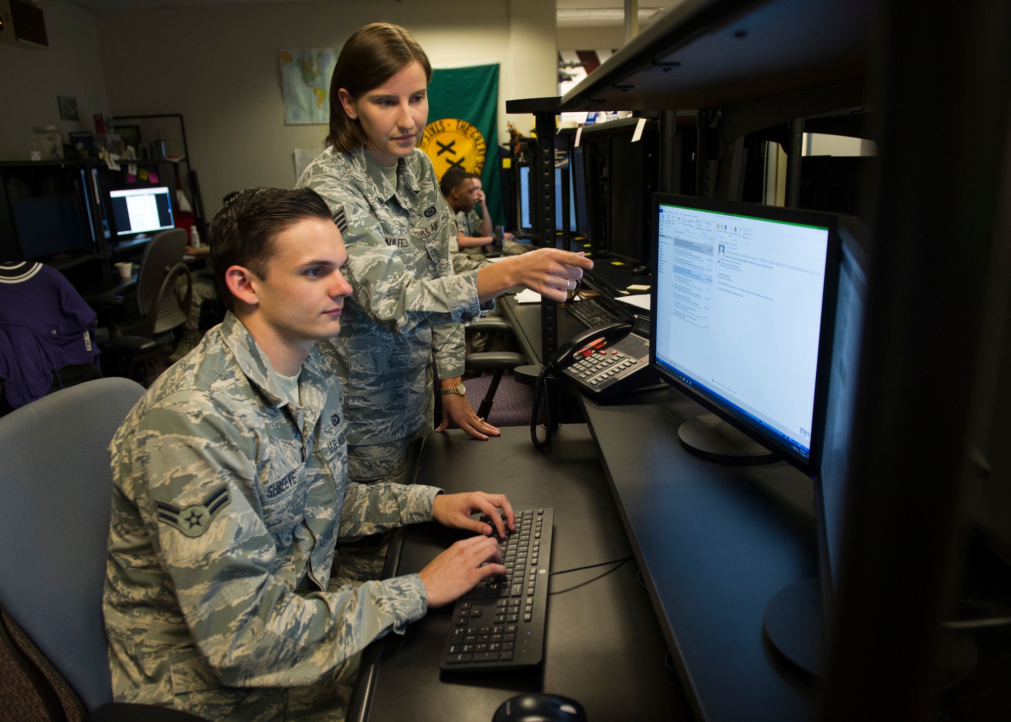 Staff Sgt. Elizabeth Caulfield, Signals Analysis Squadron scientific and technical signals analyst, mentors an Airman on mission operations July 11, 2018 at the National Air and Space Intelligence Center on Wright-Patterson Air Force Base, Ohio. Caulfield was named one of the 12 Outstanding Airmen of the Year for the Air Force. (U.S. Air Force photo/ Senior Airman Michael Hunsaker)