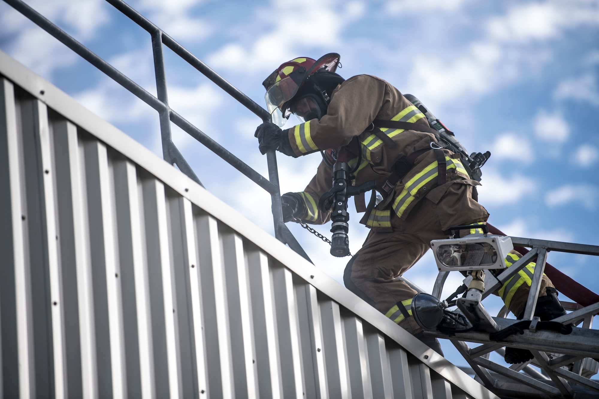 Jay Salmons, Grissom Fire Department captain, climbs atop the roof of the Smokehouse, a fire training simulator, at Grissom Air Reserve Base, Ind., Sept. 26, 2018. Grissom firefighters train in the Smokehouse frequently to practice putting out fire and rescuing victims while in a controlled, monitored environment. (U.S. Air Force photo / Senior Airman Harrison Withrow)