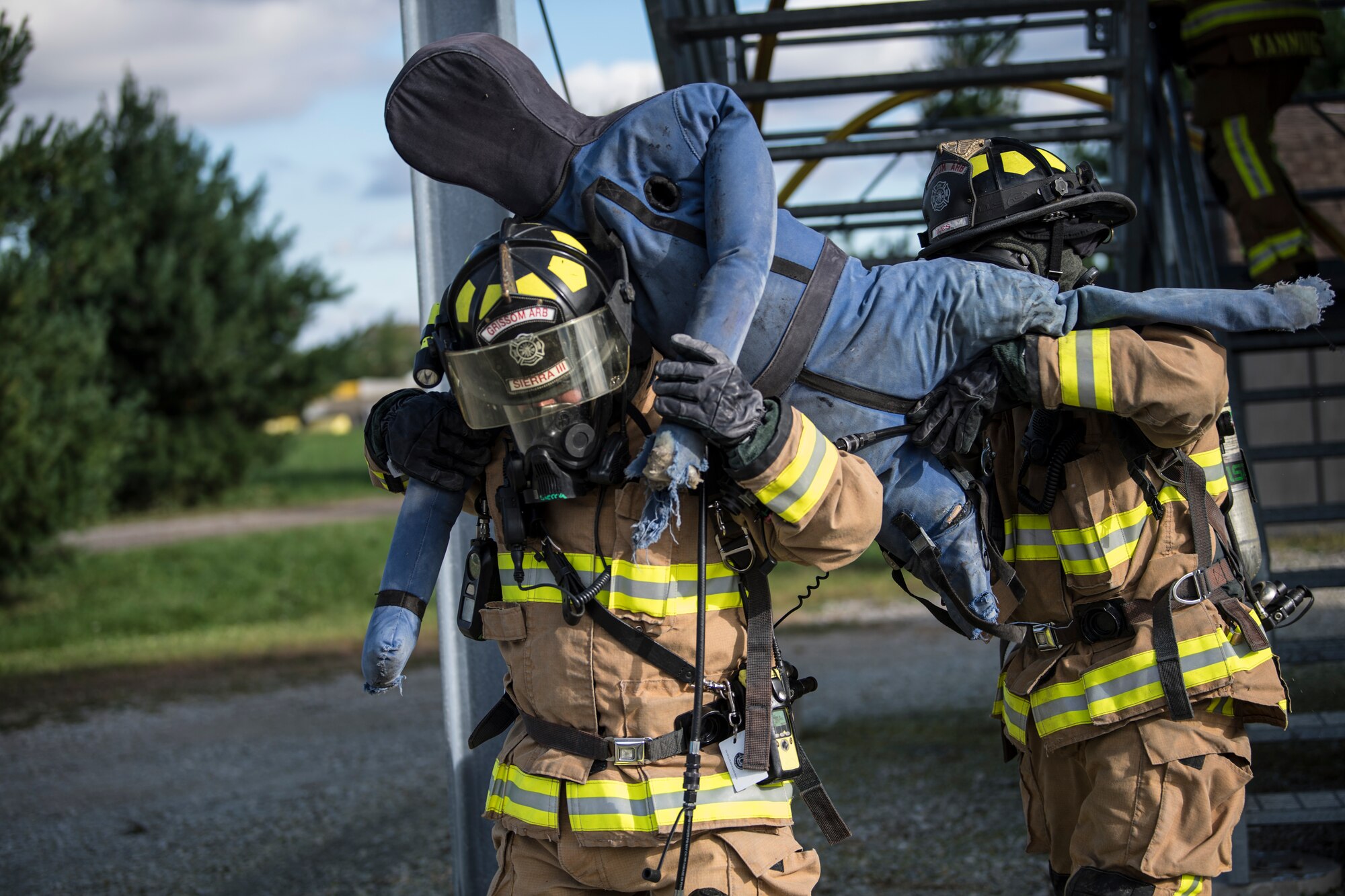 Francisco Sierra and Jeffrey Iles, Grissom Fire Department firefighters, carry a training dummy away from the Smokehouse, a fire training simulator, at Grissom Air Reserve Base, Ind., Sept. 26, 2018. Grissom firefighters train in the Smokehouse frequently to practice putting out fire and rescuing victims while in a controlled, monitored environment. (U.S. Air Force photo / Senior Airman Harrison Withrow)