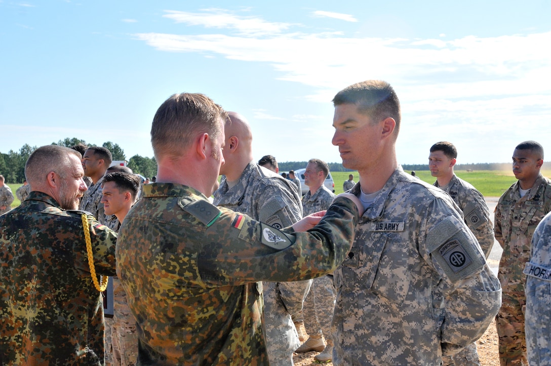A Germany army officer pins German jump wings on the uniform of a U.S. soldier.