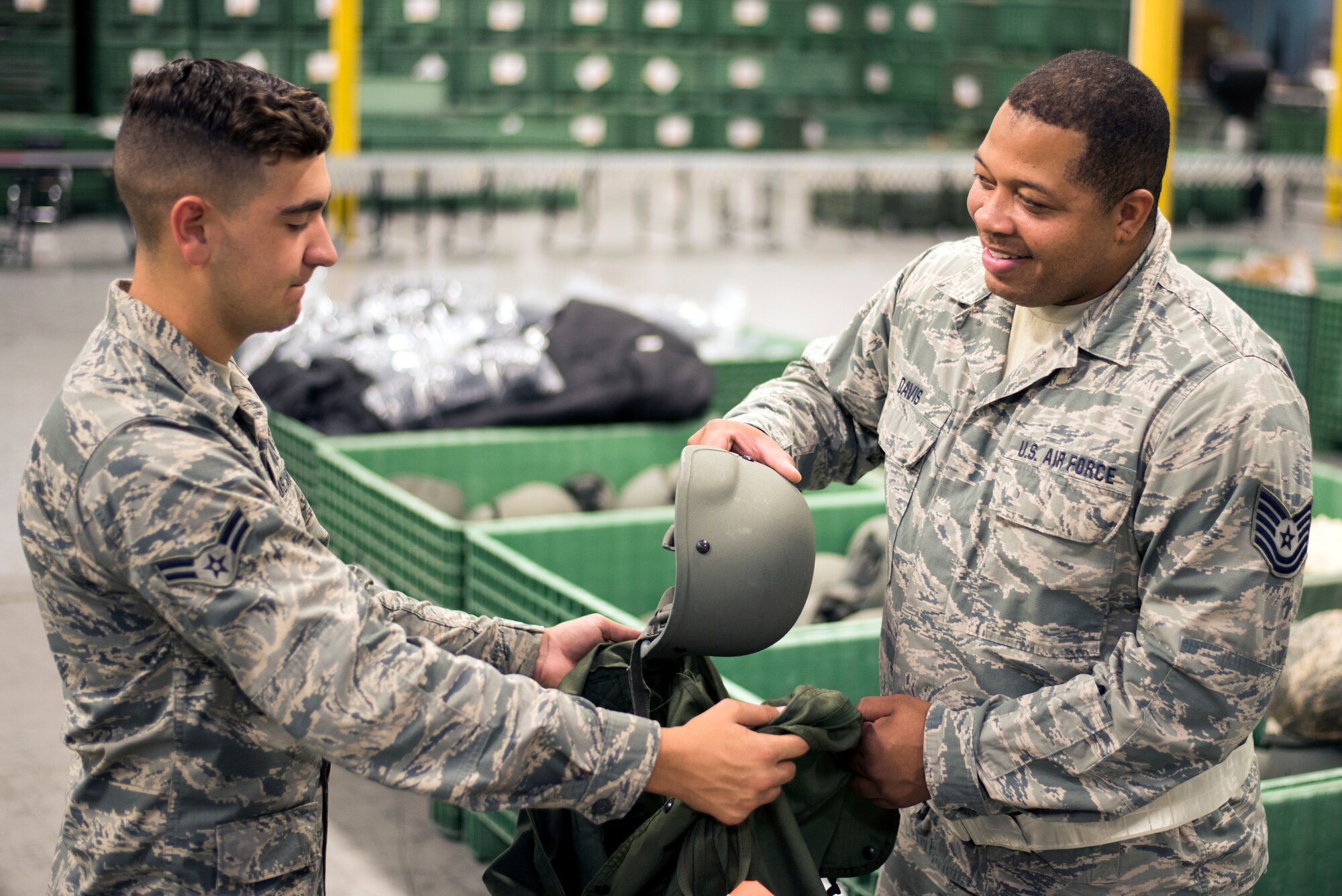 U.S. Air Force Tech Sgt. Sean Davis hands equipment to a participating Airman in a simulated personnel deployment function line during a 6th Air Mobility Wing operational readiness assessment (ORA), Oct. 2, 2018 at MacDill Air Force Base, Fla.