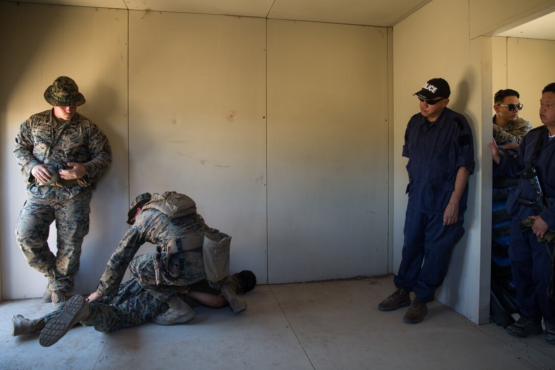 U.S. Marines with 1st Law Enforcement Battalion, Task Force Koa Moana (TF KM), demonstrate how to properly take down a detainee to a civilian role players during TF KM Mission Rehearsal Exercise at Marine Corps Base Camp Pendleton, Calif., July 17, 2018. The exercise confirms TF KM is capable of cross cultural interaction, instruction, and relationship building while training alongside partner nations in order to meet Theater Security Cooperation engagement objectives. (U.S. Marine Corps photo by Staff Sgt. Gabriela Garcia)