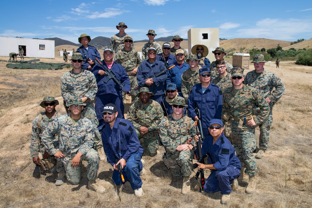 U.S. Marines with 1st Law Enforcement Battalion, Task Force Koa Moana (TF KM), and civilan role players pose for a group photo during TF KM Mission Rehearsal Exercise at Marine Corps Base Camp Pendleton, Calif., July 17, 2018. The exercise confirms TF KM is capable of cross cultural interaction, instruction, and relationship building while training alongside partner nations in order to meet Theater Security Cooperation engagement objectives. (U.S. Marine Corps photo by Staff Sgt. Gabriela Garcia)