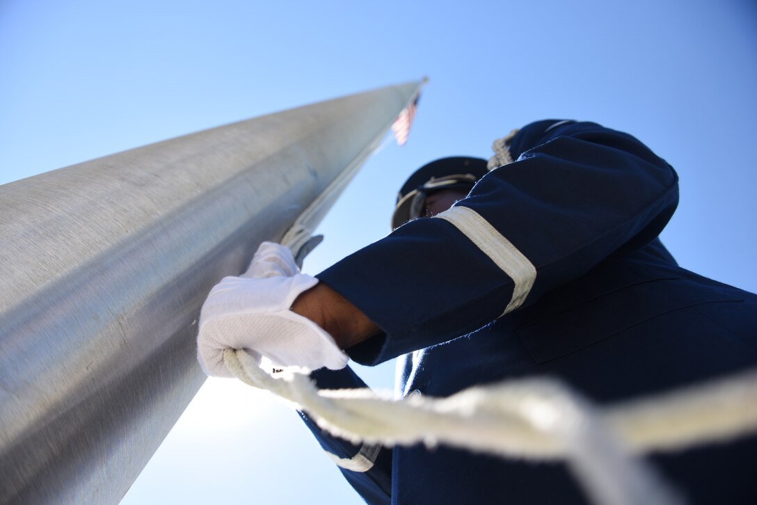 An airman lowers a flag.