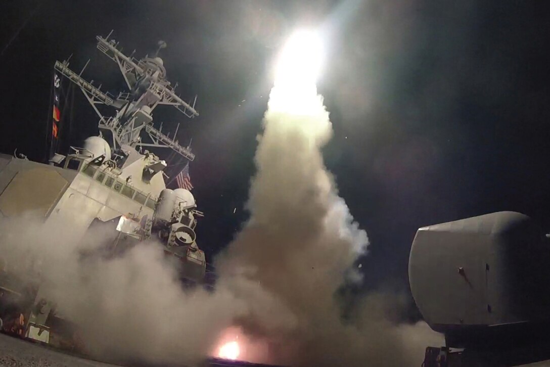 A missile launches from a ship at night.