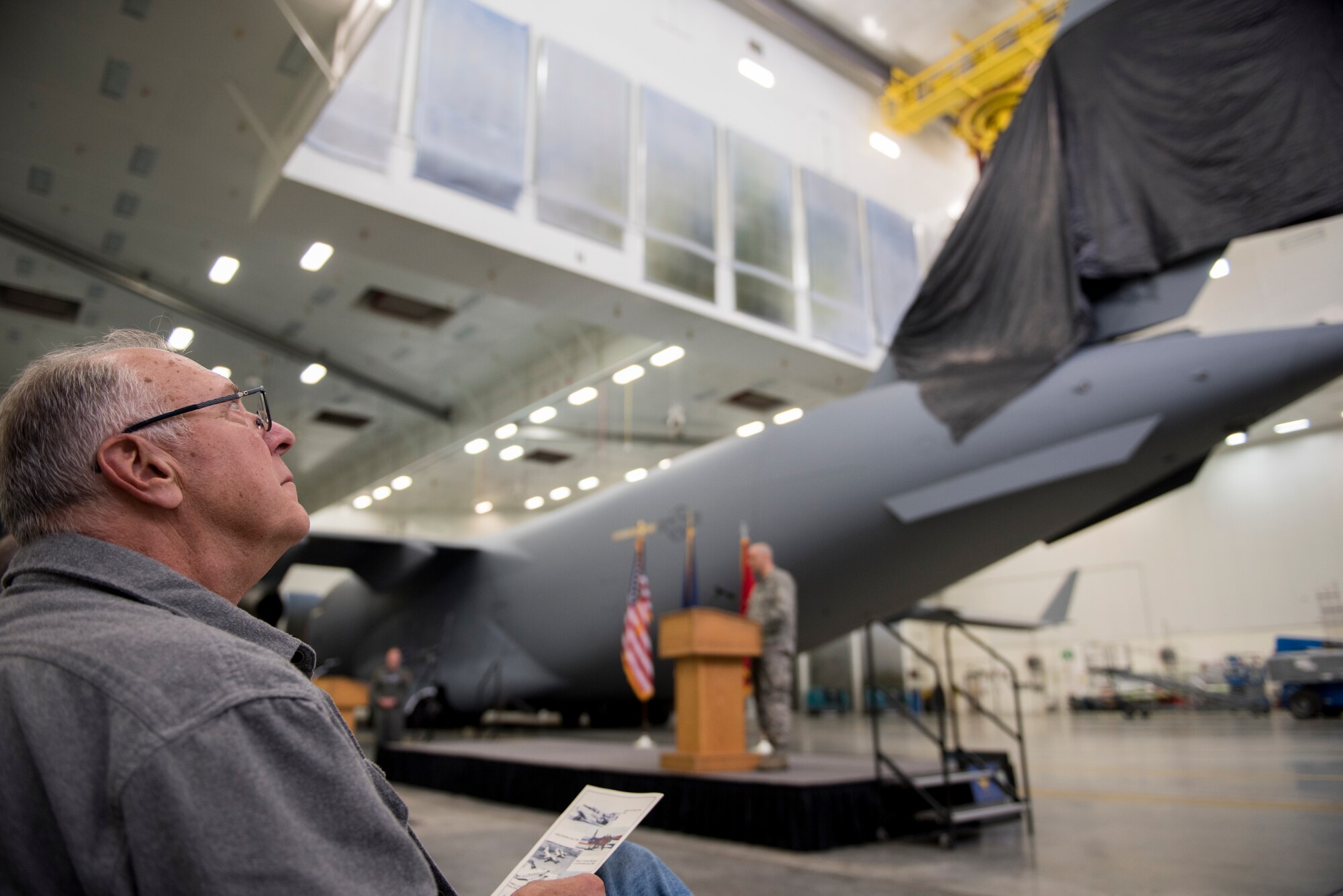 Retired Master Sgt. Don Frederick, a prior CATM instructor with the 176th Security Forces Squadron, awaits the unveiling of a new tail flash here Oct. 1, 2018 on the C-17 Globemaster IIIs assigned to the 176th Wing’s 144th Airlift Squadron. The new tail flash depicts a wolf head, (the 144th AS’s emblem), on one side, and a firebird (the 517th AS’s emblem), of equal size on the other. (U.S. Air National Guard photo by Tech. Sgt. N. Alicia Halla)