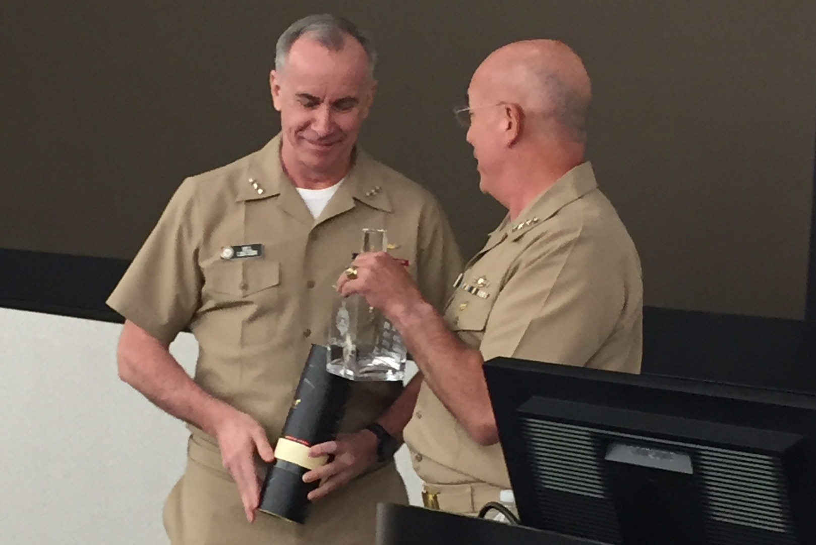 Navy Adm. Kurt Tidd passes the Old Goat Award decanter to Vice Adm. Bill Lesher during an unofficial ceremony at the Washington Navy Yard.