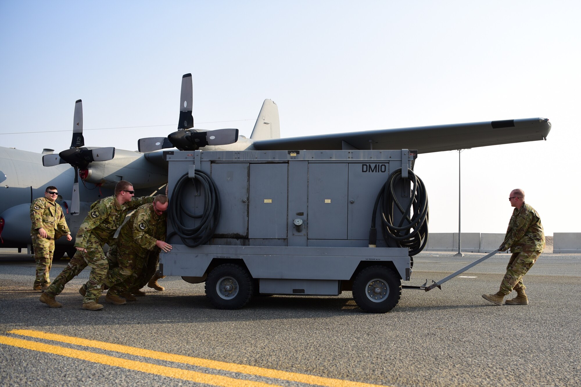 Maintainers from the 386th Expeditionary Aircraft Maintenance Squadron drag a ground power unit away from a 43rd Expeditionary Electronic Combat Squadron EC-130 aircraft Sept. 21, 2018, at an undisclosed location in Southwest Asia. The EC-130 aircraft serves as a tactical weapon system since 1981 and has been modified through the years. Each update has provided the platform stronger avionics systems, radars and more powerful digital signal analysis computers and subsystems. (U.S. Air Force photo by Staff Sgt. Christopher Stoltz)