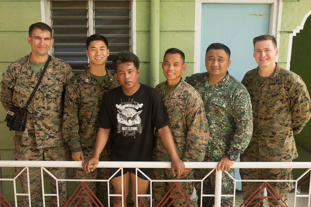 U.S. Marine Corps Capt. Mark Hanford and Sgt. Nicholas Elston, U.S. Navy Lt. Maundo Lee and Brian Bonzo, and Philippine Marine Corps Capt. Rodilson Malic, pose for a photo with Philippine local, Bryan S. Rodriguez, who they assisted after a motorcycle crash in Ternate, Cavite, Philippines, Oct. 2, 2018.