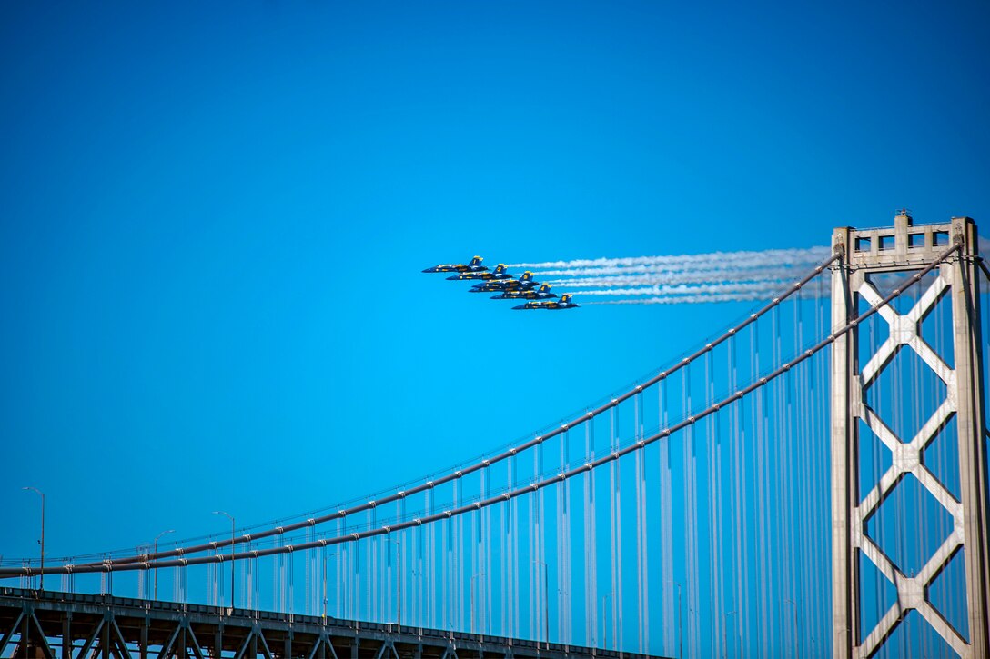 The Blue Angels fly over the San Francisco-Oakland bridge in formation.