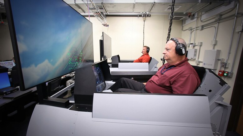 Scott Carpenter and Donald Simones, both subject matter experts in the Air Force Research Laboratory’s 711th Human Performance Wing, fly virtual F-16s in Deployable Tactical Trainers. The live aircraft were able to see and interact with the virtual players during Phase III of the Secure Live Virtual Constructive Advanced Training Environment (SLATE) demonstration at Nellis Air Force Base, Nevada, in September. (U.S. Air Force photo/William Graver)