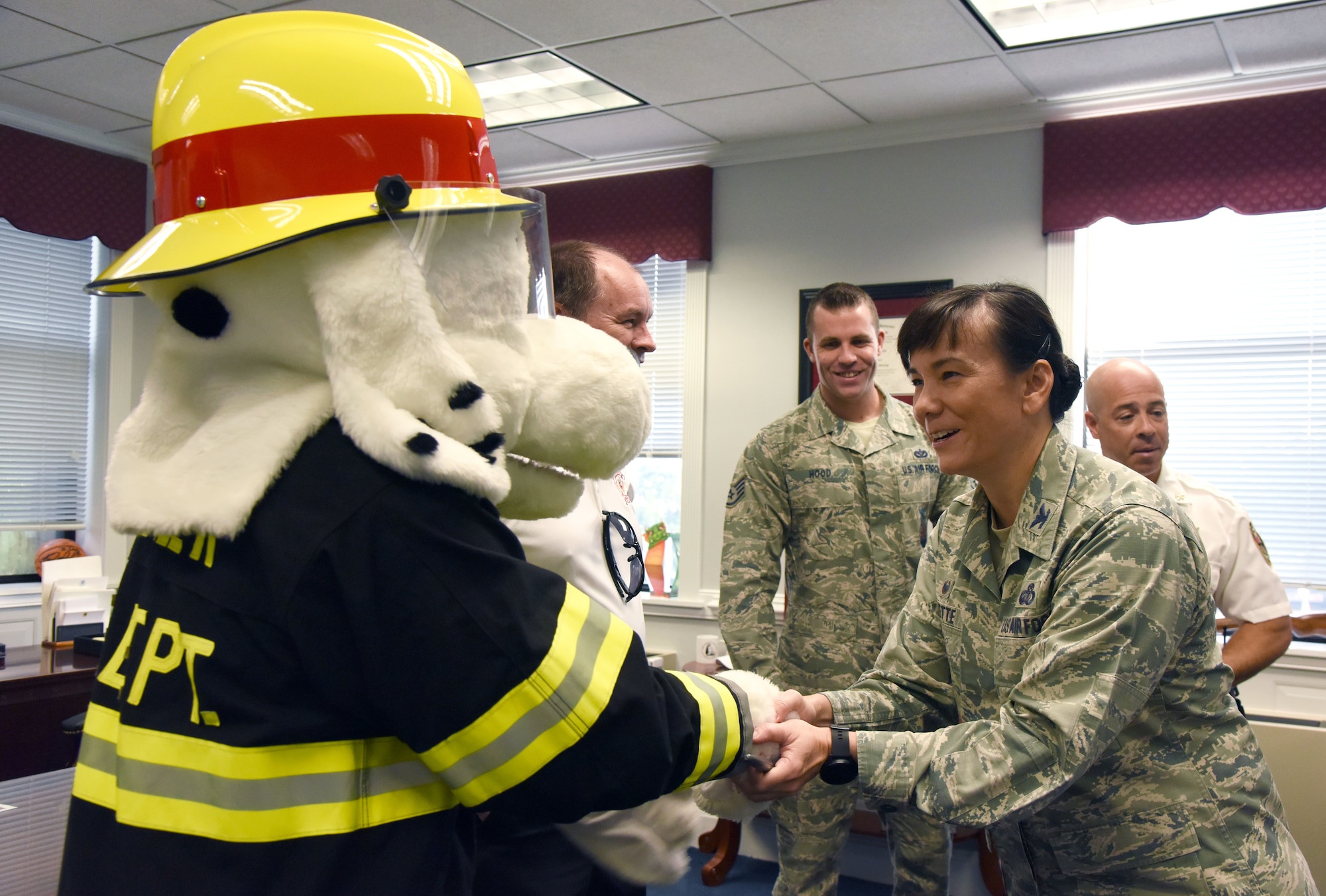 U.S. Air Force Col. Debra Lovette, 81st Training Wing commander, greets Sparky the Fire Dog during the kickoff of Fire Prevention Week at the 81st TRW headquarters building on Keesler Air Force Base, Mississippi, Oct. 9, 2018. The week-long event includes fire drills, literature hand-outs and stove fire demonstrations around the base and concludes with an open house at the fire department Oct. 13. (U.S. Air Force photo by Kemberly Groue)