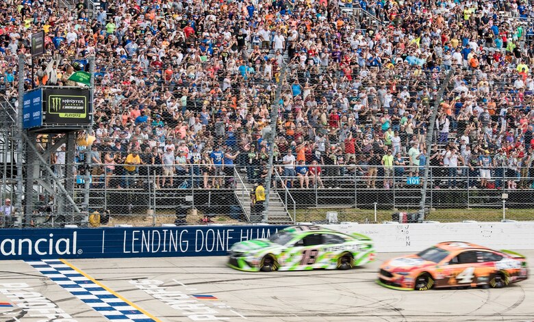 Tech. Sgt. Michael Kelly (top left), 736th Aircraft Maintenance Squadron C-17 Globemaster III flight line expediter, waves the green flag for the start of the "Gander Outdoors 400" Monster Energy NASCAR Cup Series race Oct. 7, 2018, at Dover International Speedway in Dover, Del. Kelly waved the flag as the row one cars, No. 18 Kyle Busch and No. 4 Kevin Harvick, head to the starting line. (U.S. Air Force photo by Roland Balik)