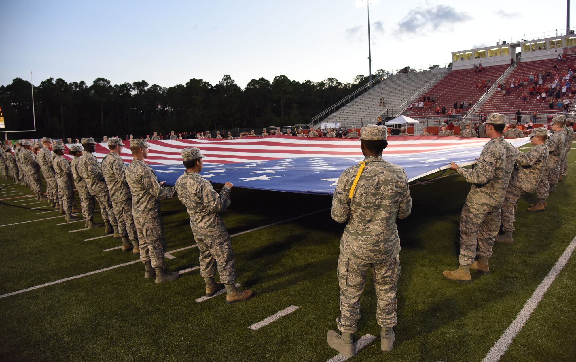 Keesler Airmen hold the U.S. Flag during the playing of the national anthem at the Biloxi High School military appreciation night football game in Biloxi, Mississippi, Oct. 5, 2018. Keesler personnel also participated in the coin toss to determine which team would receive the ball first. (U.S. Air Force photo by Kemberly Groue)