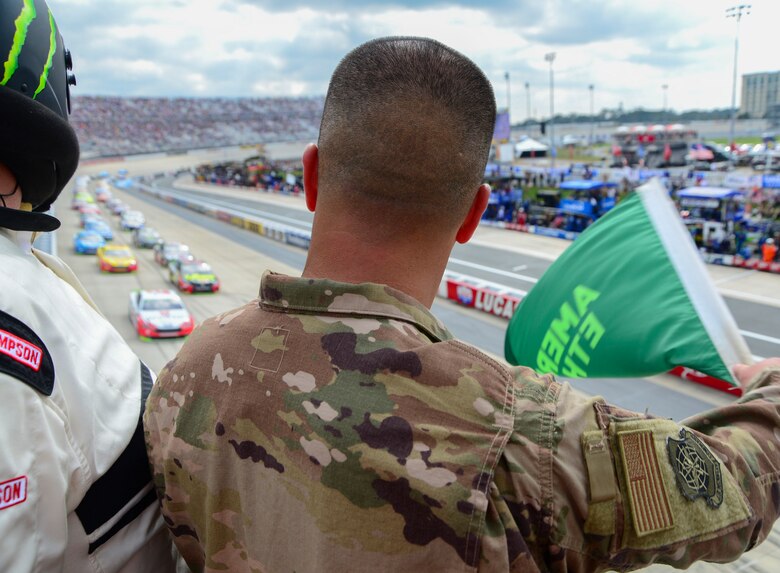 Tech. Sgt. Michael Kelly, 736th Aircraft Maintenance Squadron, C-17 Globemaster III flightline expediter, waves the green flag at the start of the “Gander Outdoors 400” Monster Energy NASCAR Cup Series race Oct. 7, 2018, at the Dover International Speedway in Dover, Del. Kelly was selected for this honor on behalf of the NASCAR and DIS track officials to honor his military service and represented Dover Air Force Base in front of hundreds of thousands of viewers on national television. (U.S. Air Force photo by Airman First Class Dedan D. Dials)