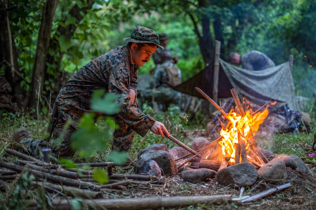 A sailor builds a fire in the jungle.
